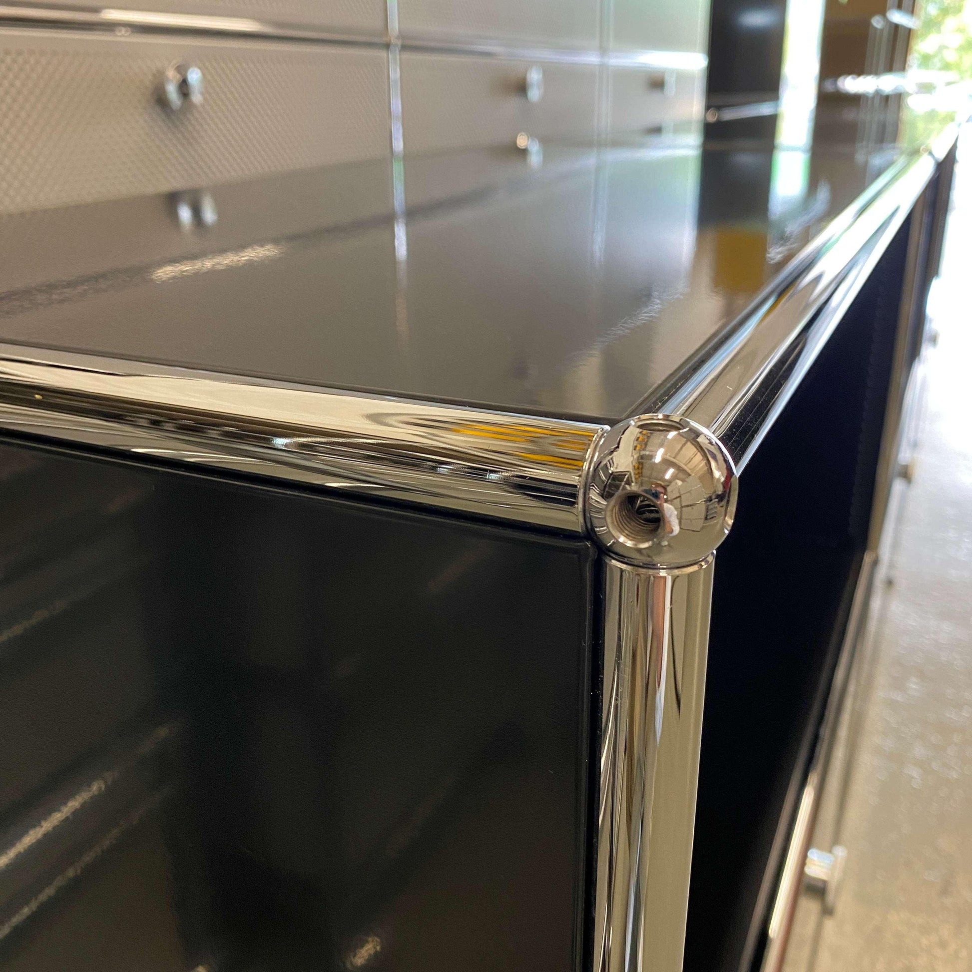 Close-up of black USM Haller Sideboard with three flap doors and chrome frame detailing