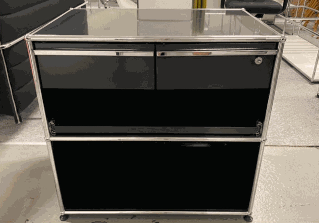 USM Haller Sideboard in graphite black with chrome frame, featuring drawers and a cabinet, modern and functional design.