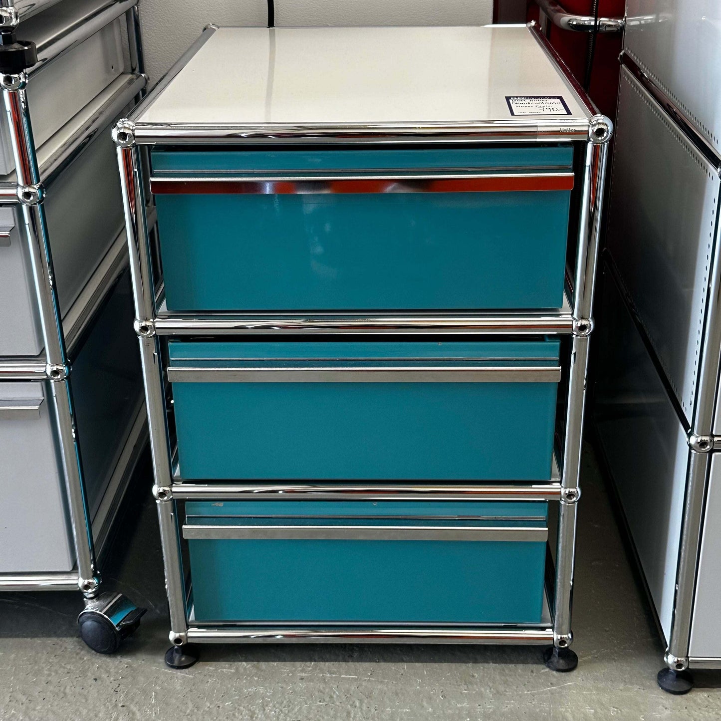 USM Haller Standcontainer with three turquoise drawers and light gray top in chrome frame