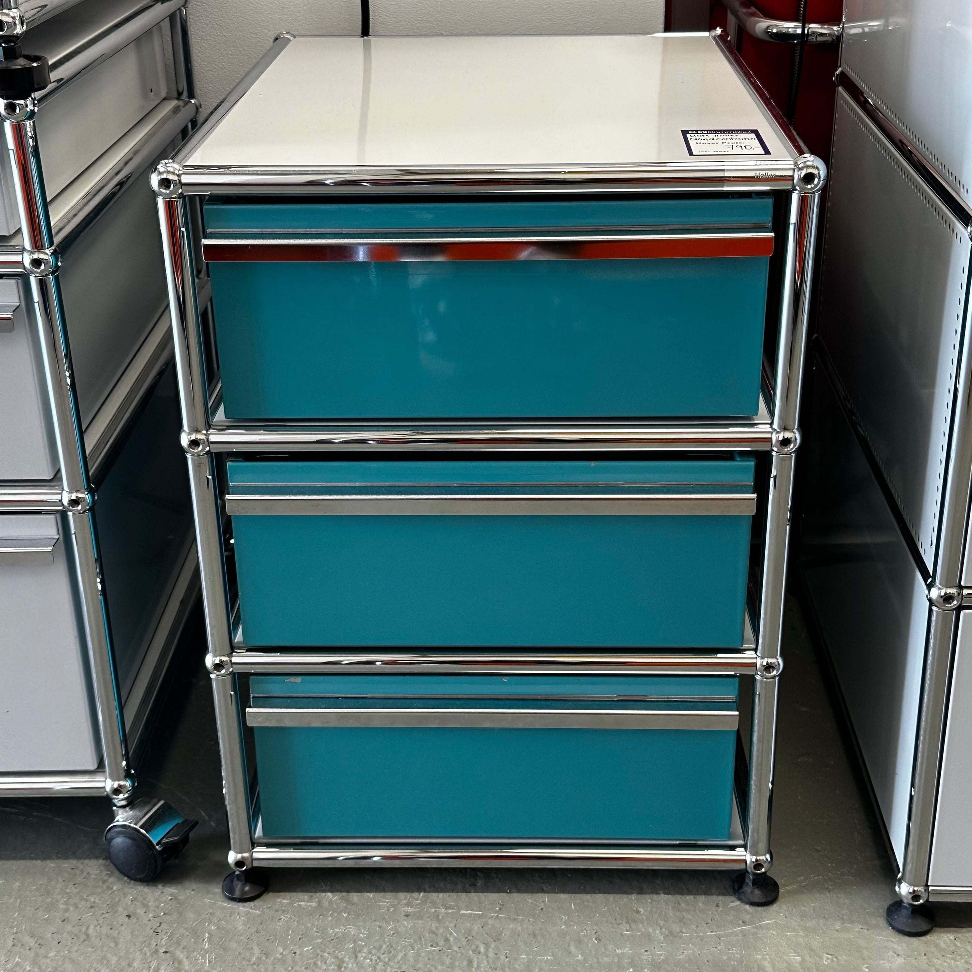 USM Haller Standcontainer with three turquoise drawers and light gray top in chrome frame