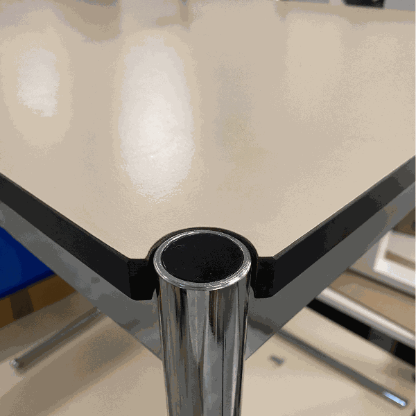 Close-up of USM Haller Tisch beige table corner with chrome frame and beige tabletop, 150x75cm size