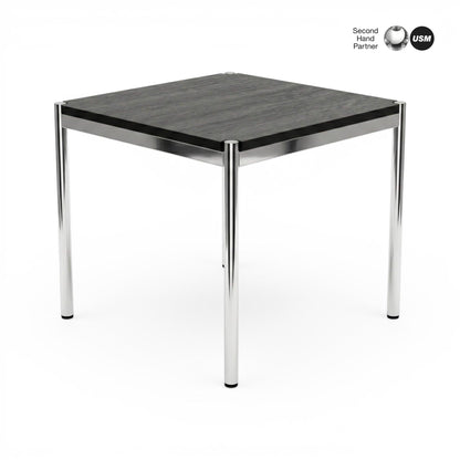 USM Haller Tisch 70x70cm, schwarze Eichenplatte mit sichtbarer Maserung, auf glänzenden Chrombeinen.