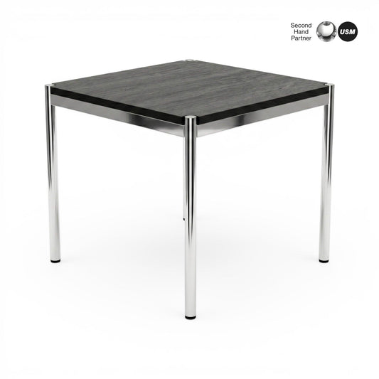 USM Haller Tisch 70x70cm, schwarze Eichenplatte mit sichtbarer Maserung, auf glänzenden Chrombeinen.