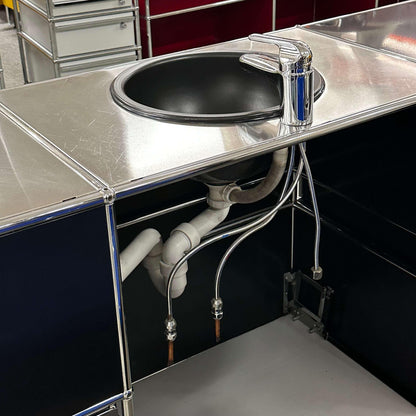 USM Haller Waschtisch black and stainless steel sink unit with three flaps, two drawers, open shelves, and plumbing connection
