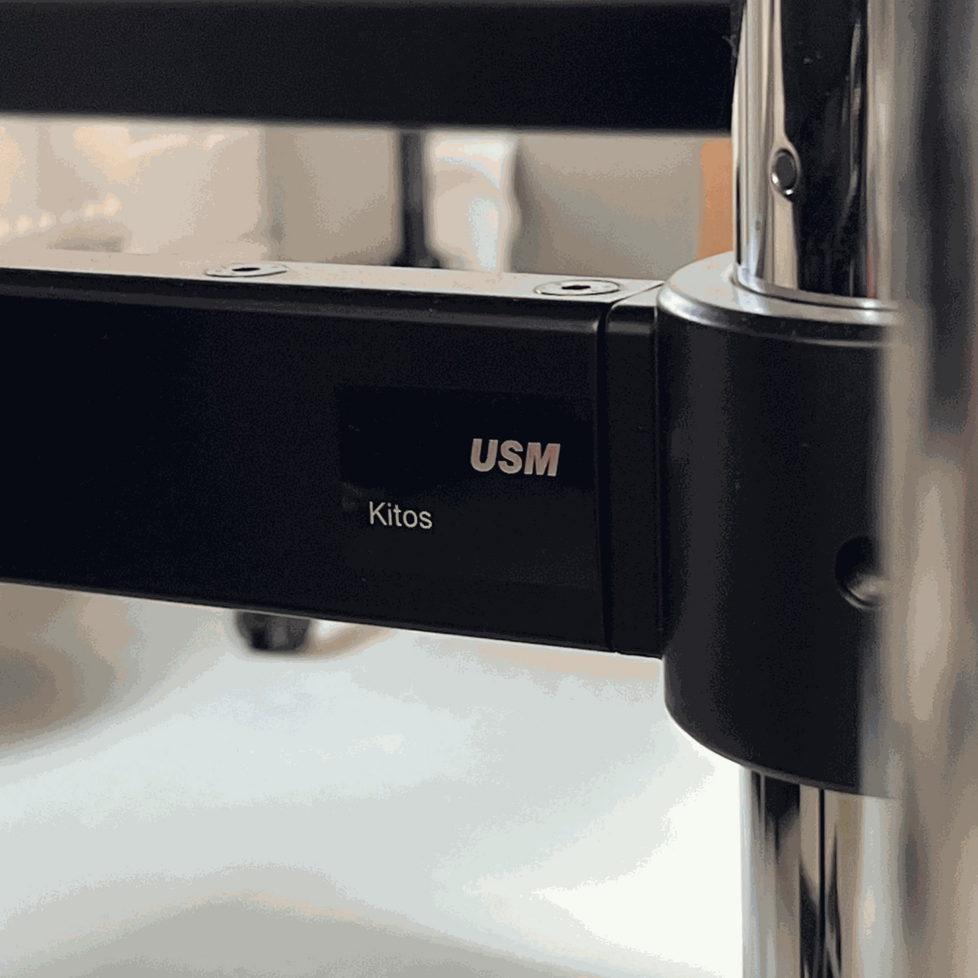 Close-up of USM Kitos E2 electric height-adjustable desk frame in black with logo and metal support details.