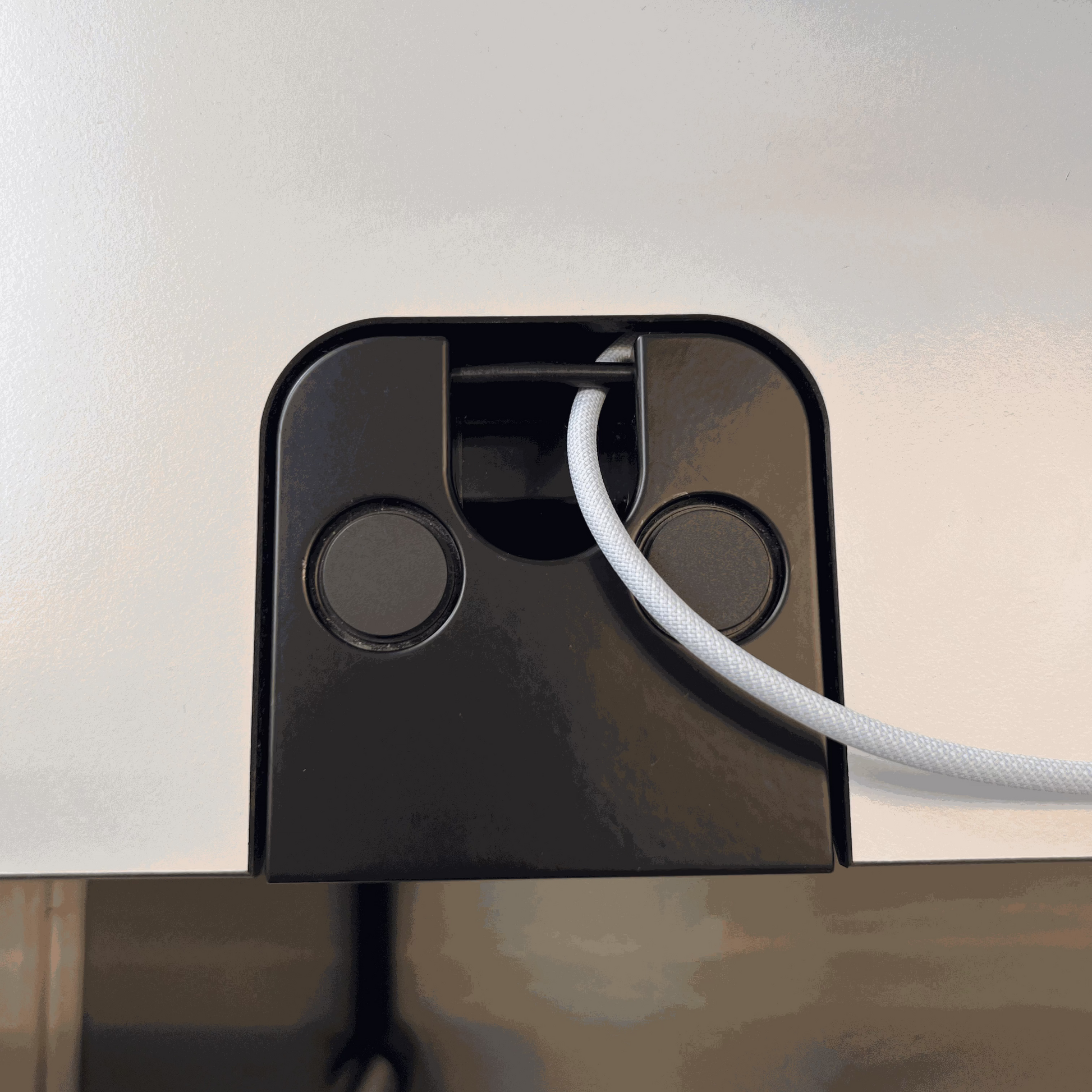 Close-up of USM Kitos E2 electric height-adjustable desk cable management system with white cable slot in black housing on pearl gray resin tabletop