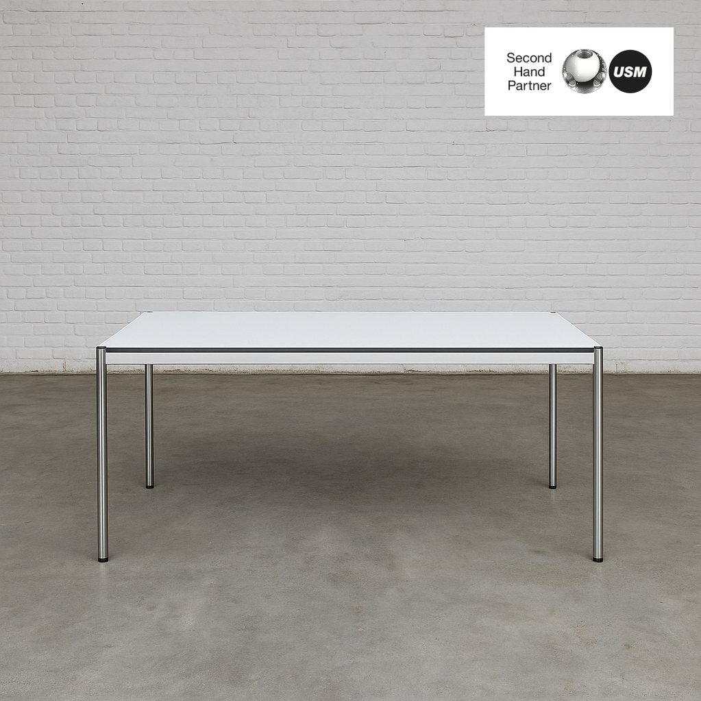 USM Haller Tisch 200x100cm perlgrau weiß mit Stahlgestell und optionalem Zubehör vor weißer Ziegelwand