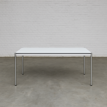USM Haller Tisch 200x100cm perlgrau weiß mit Stahlgestell und optionalem Zubehör vor weißer Ziegelwand