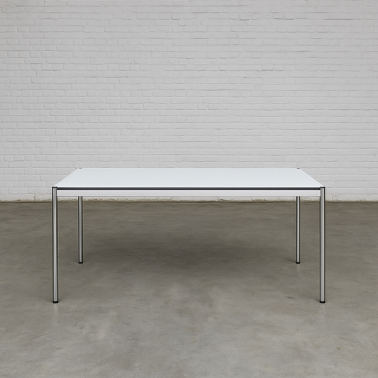 USM Haller Tisch 200x100cm perlgrau weiß mit Stahlgestell und optionalem Zubehör vor weißer Ziegelwand