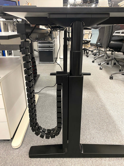 Vario Change 180x80cm electric height adjustable desk with black C-leg frame and cable management system in office setting