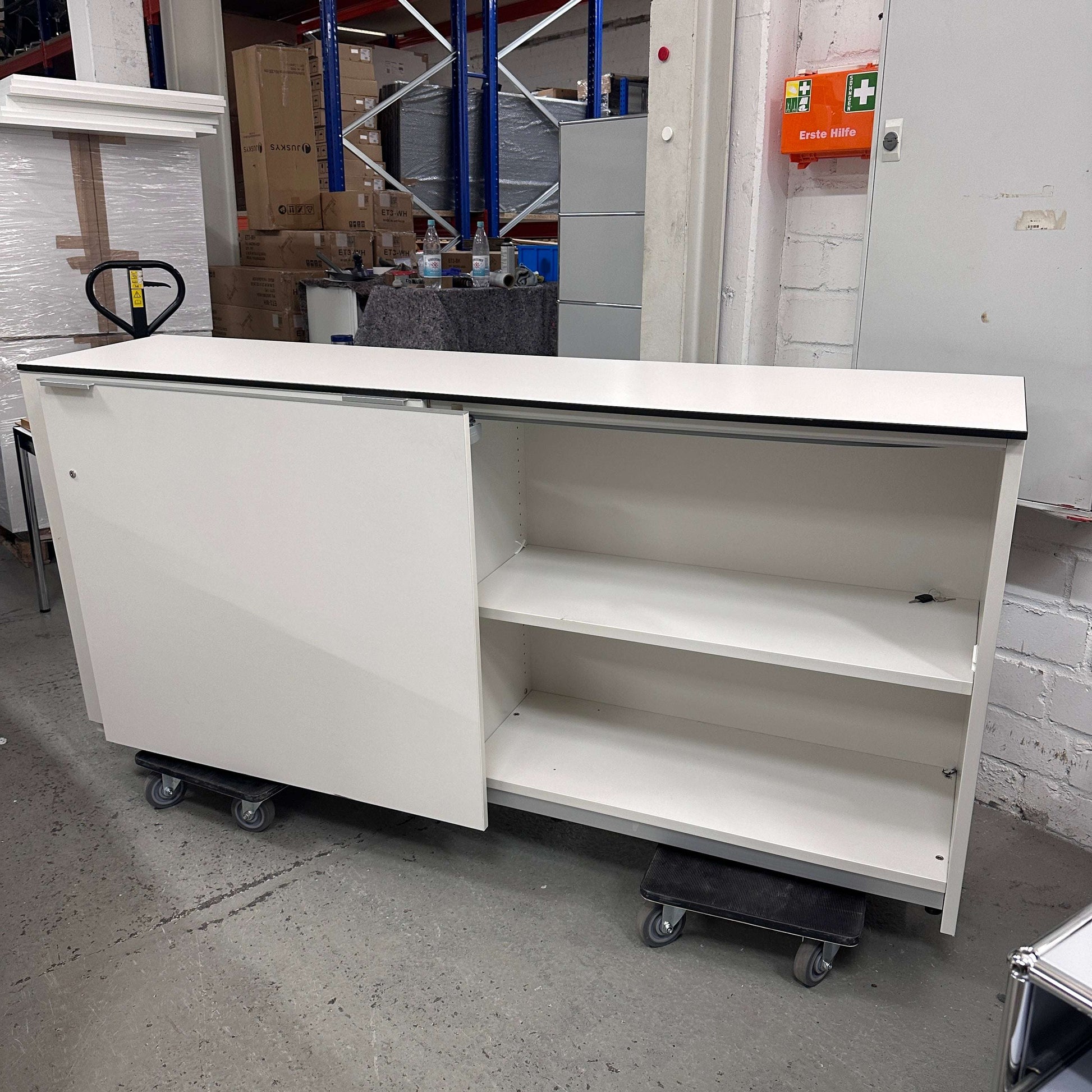 Vario M9 Sideboard 2OH in premiumweiß mit Schwebetürenschrank, abschließbar, Maße 220x43x71 cm in Lagerumgebung