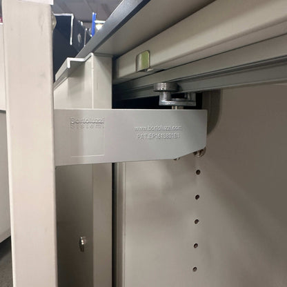 Detailaufnahme des Schiebetürmechanismus des weißen Vario M9 Sideboard 2OH Schranksystems mit Bandazuzi Beschlag.