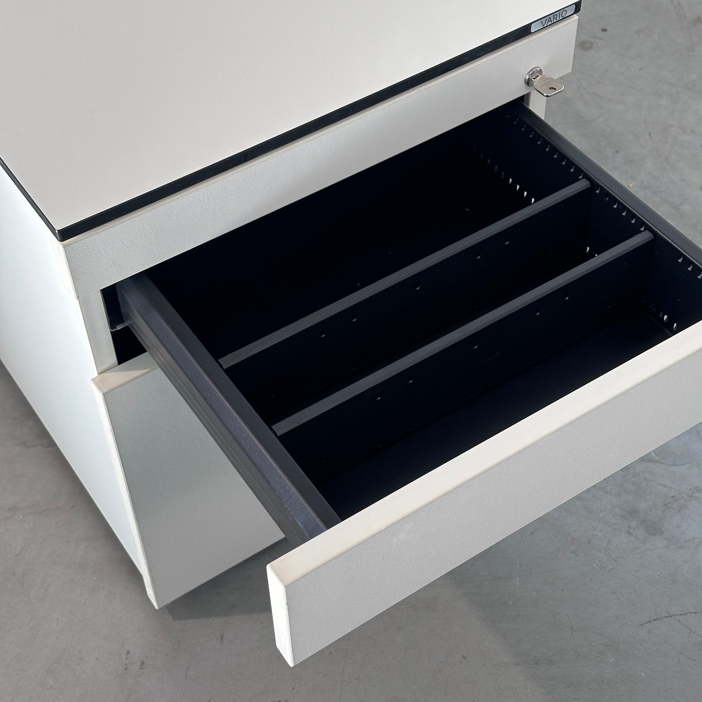 Weißer Vario Rollcontainer mit drei Schubladen, schwarzer Kante und offener Stiftschublade, 44x51x80 cm.