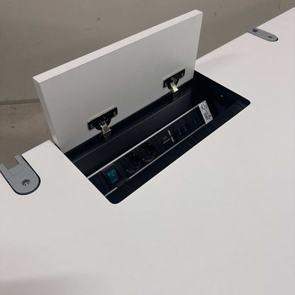Vario Stage Schreibtisch mit weißer Platte, chromfarbener Gestell, integrierter Kabelführung und Bachmann Steckdosenleiste mit USB-Anschlüssen.