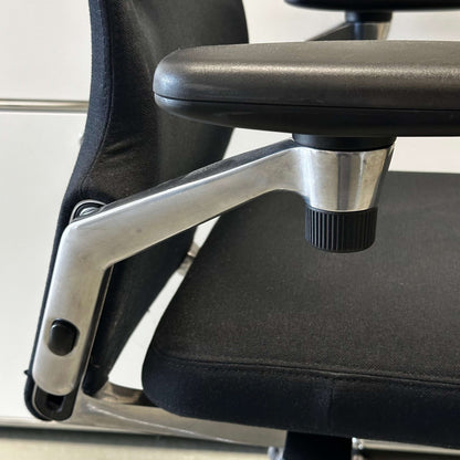 Close-up of Vitra AC 4 office chair armrest in black fabric with chrome frame detailing