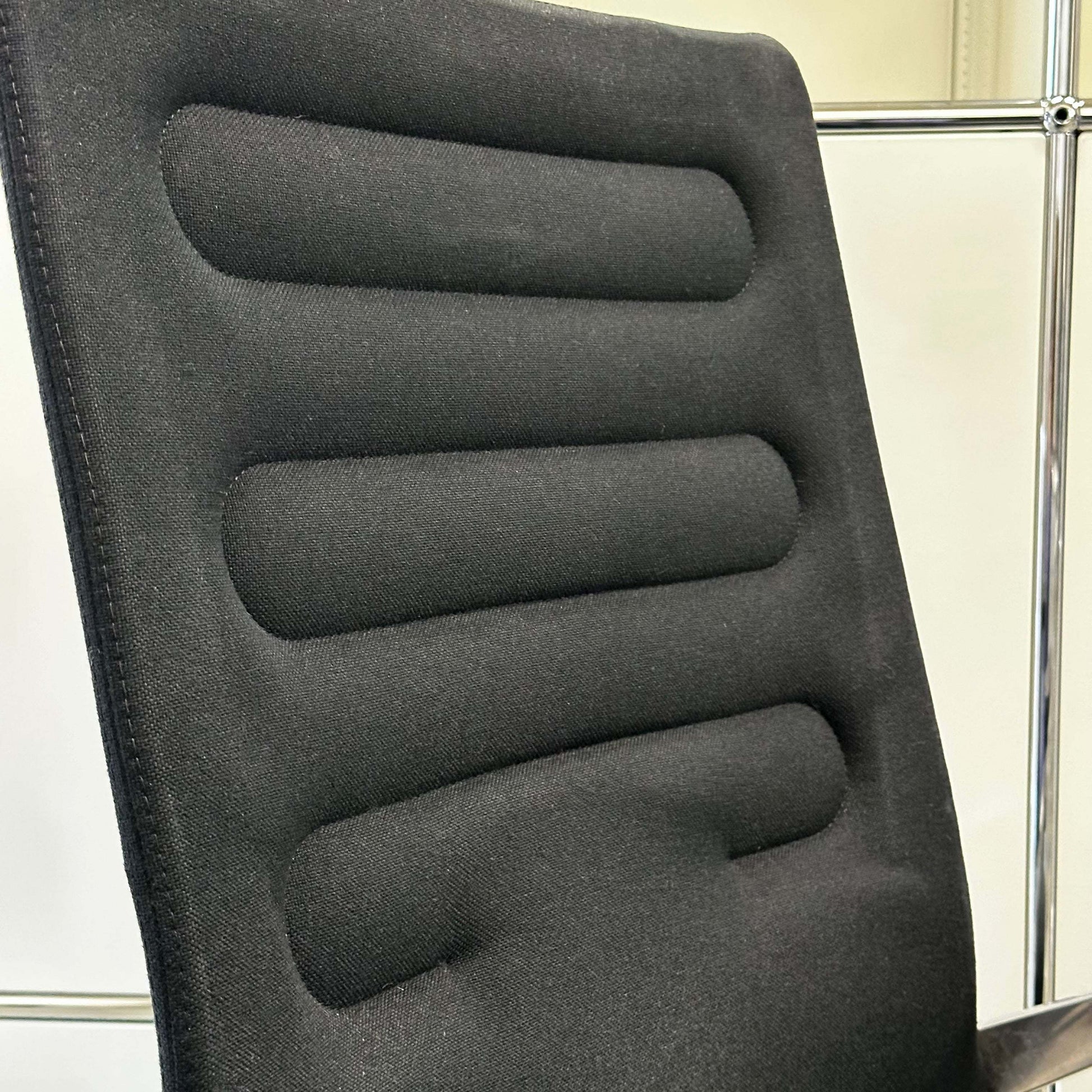 Close-up of black Vitra AC 4 office chair with padded backrest and chrome frame