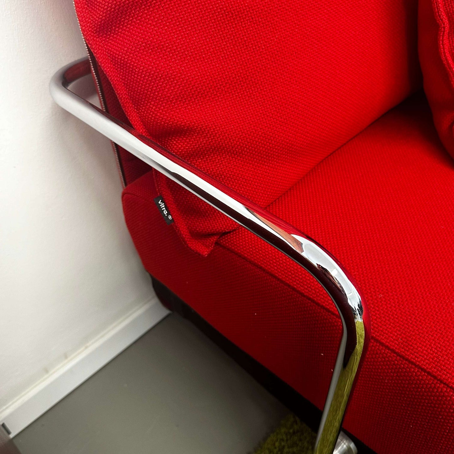 Close-up of red Vitra Alcove Ecke corner sofa with chrome armrest, expandable design