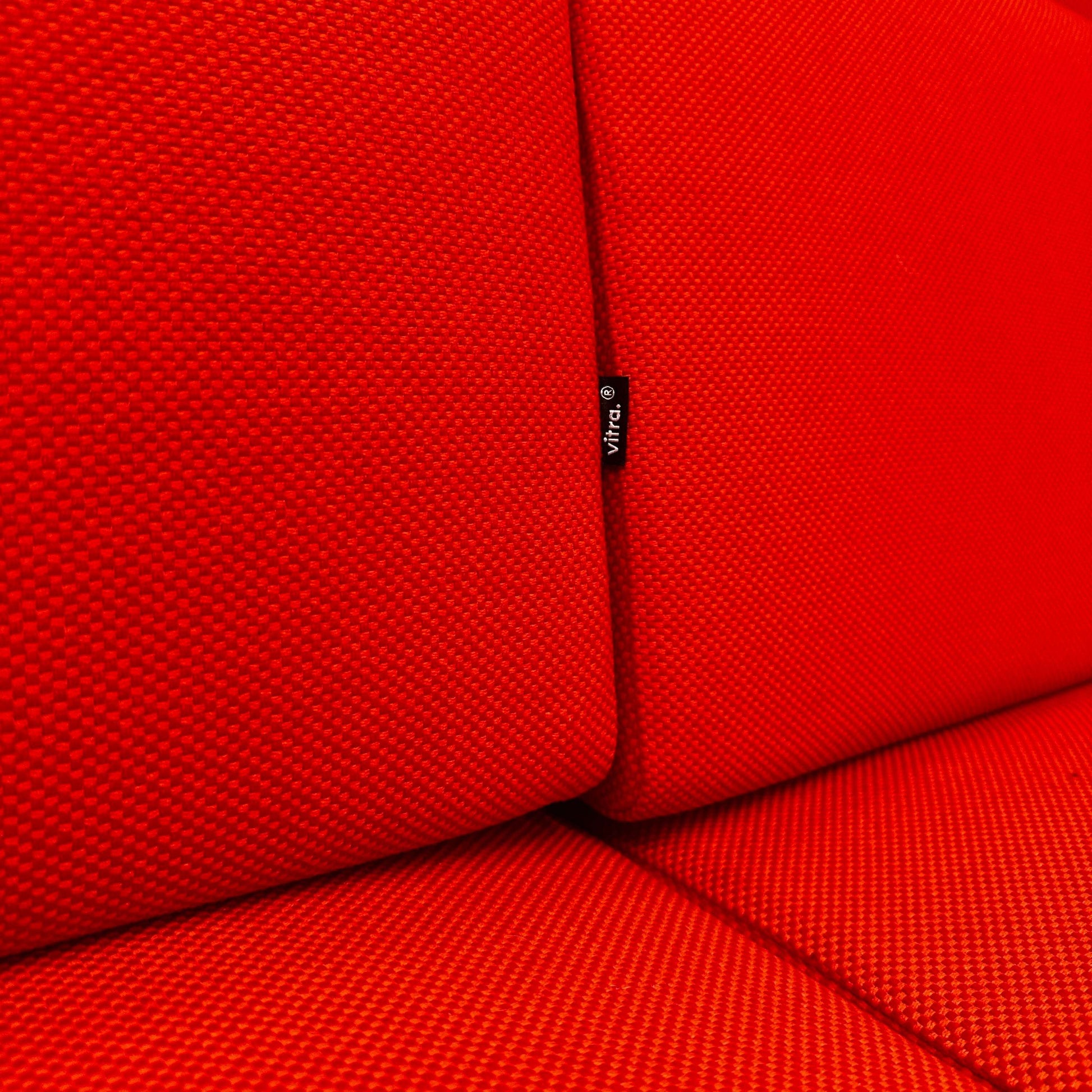 Nahaufnahme des roten Stoffbezugs am Vitra Alcove Highback 3-Sitzer Sofa mit robustem Recycling-Polyester und chromgestell.