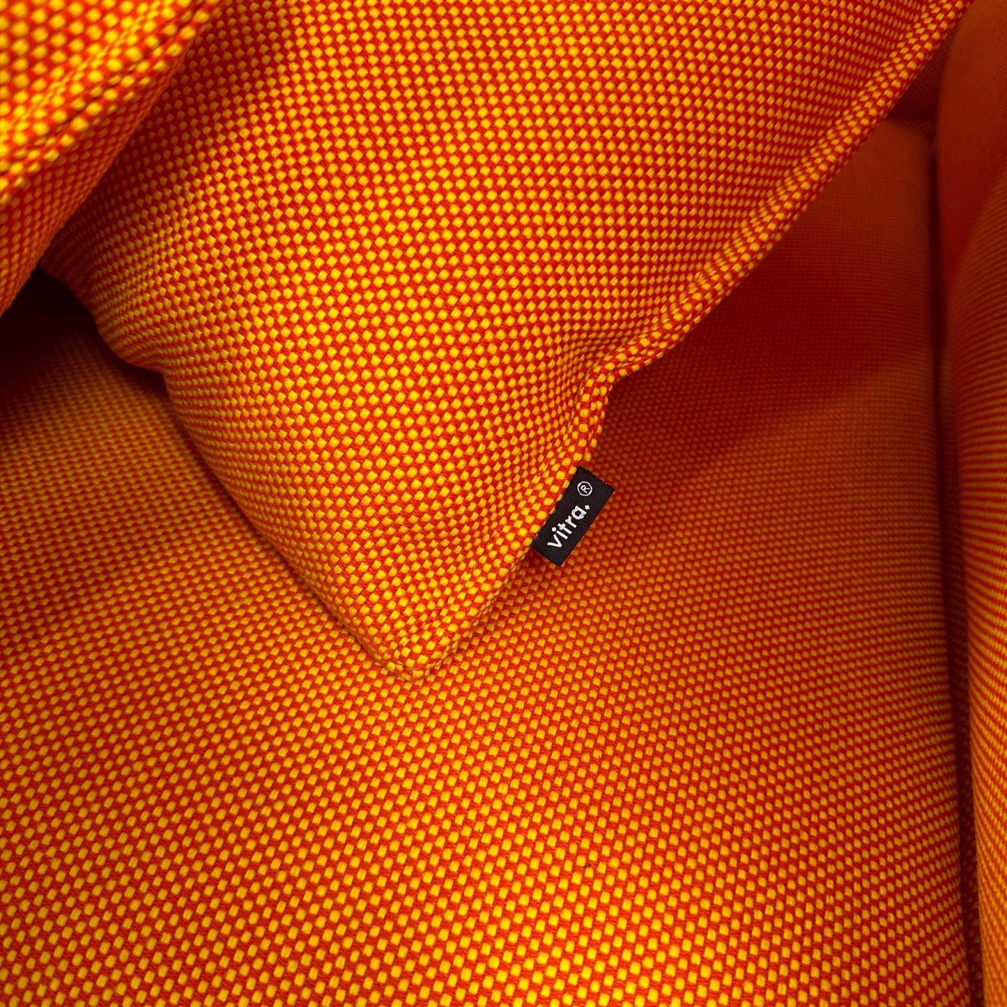 Nahaufnahme von oranger Vitra Alcove Highback Loveseat Stoffoberfläche mit Vitra-Logo-Tag