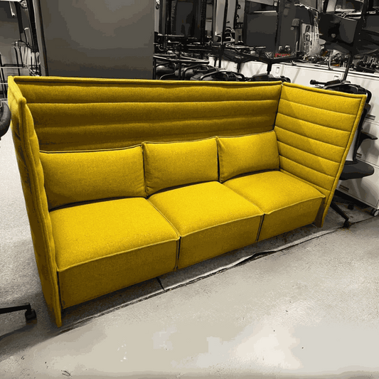 Yellow Vitra Alcove Highback Plume Contract three-seater sofa with high cushioned back and side panels in modern office setting