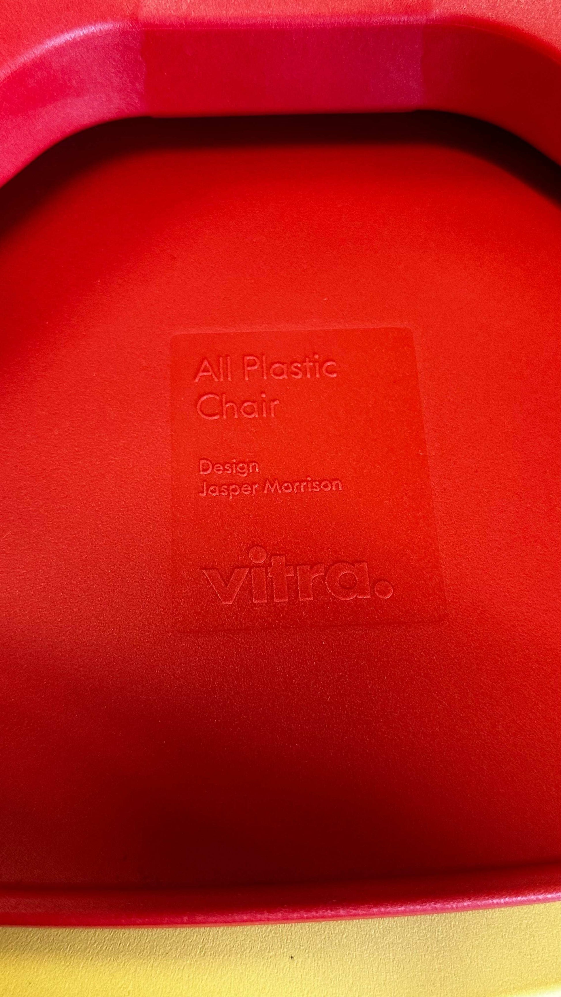 Close-up of red Vitra All Plastic Chair seat with embossed branding and designer name Jasper Morrison