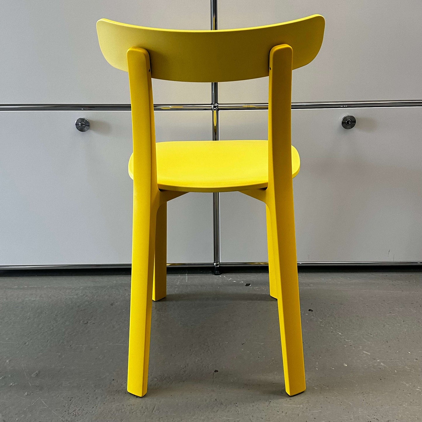 Back view of Vitra All Plastic Chair in bright Butterblume yellow, modern minimalist design for indoor and outdoor use