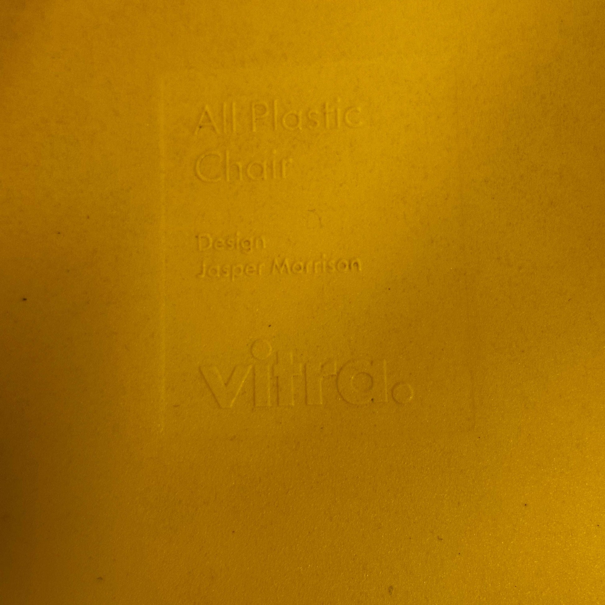 Close-up of embossed text on yellow Vitra All Plastic Chair designed by Jasper Morrison, in Butterblume color
