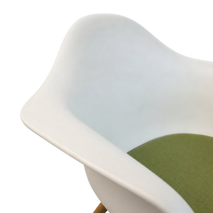 Detailansicht der weißen Vitra Eames DAW Sitzschale mit grünem Polster und Ahornholz-Beinen.