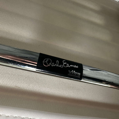 Close-up of Vitra EA 101 chair chrome frame with Charles Eames signature badge on white leather upholstery