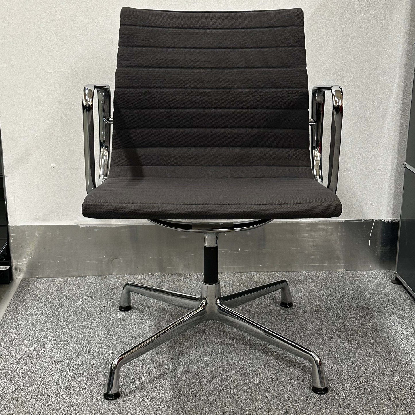 Vitra EA 107 anthracite visitor chair with non-swivel base and sleek chrome arms in minimalist office setting
