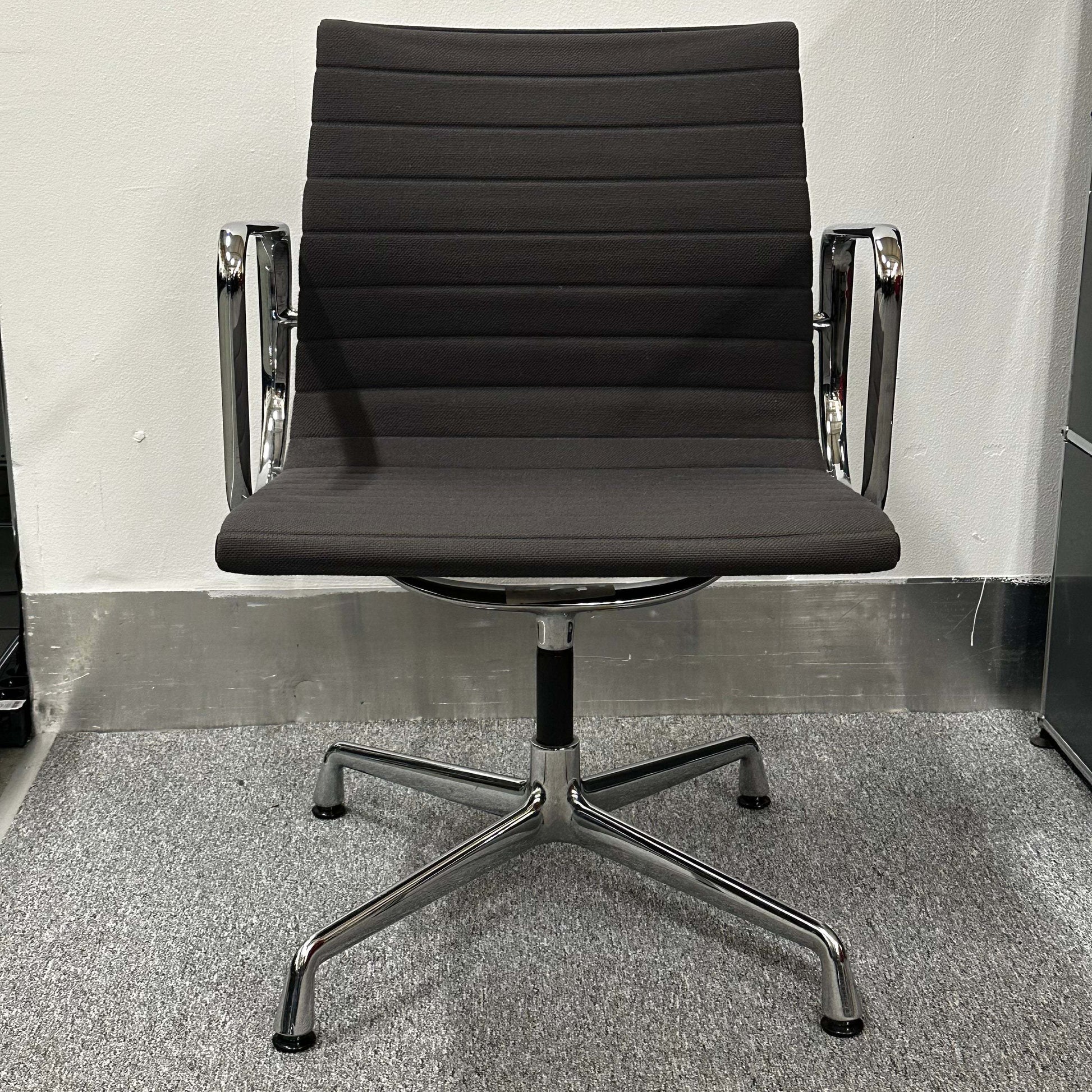 Vitra EA 107 anthracite visitor chair with non-swivel base and sleek chrome arms in minimalist office setting