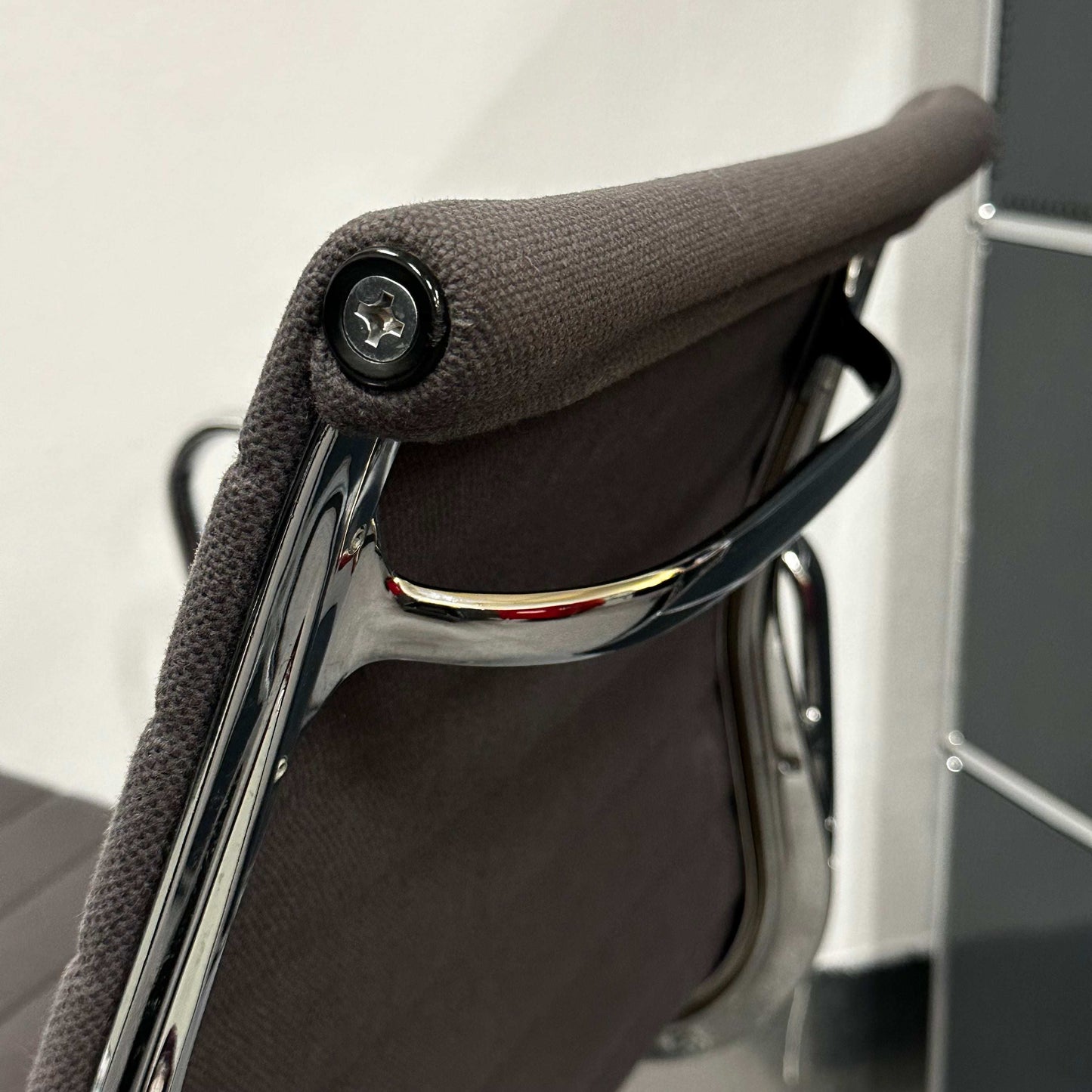 Close-up of the backrest and chrome frame of the Vitra EA 107 anthracite visitor chair with non-swivel hopsak upholstery