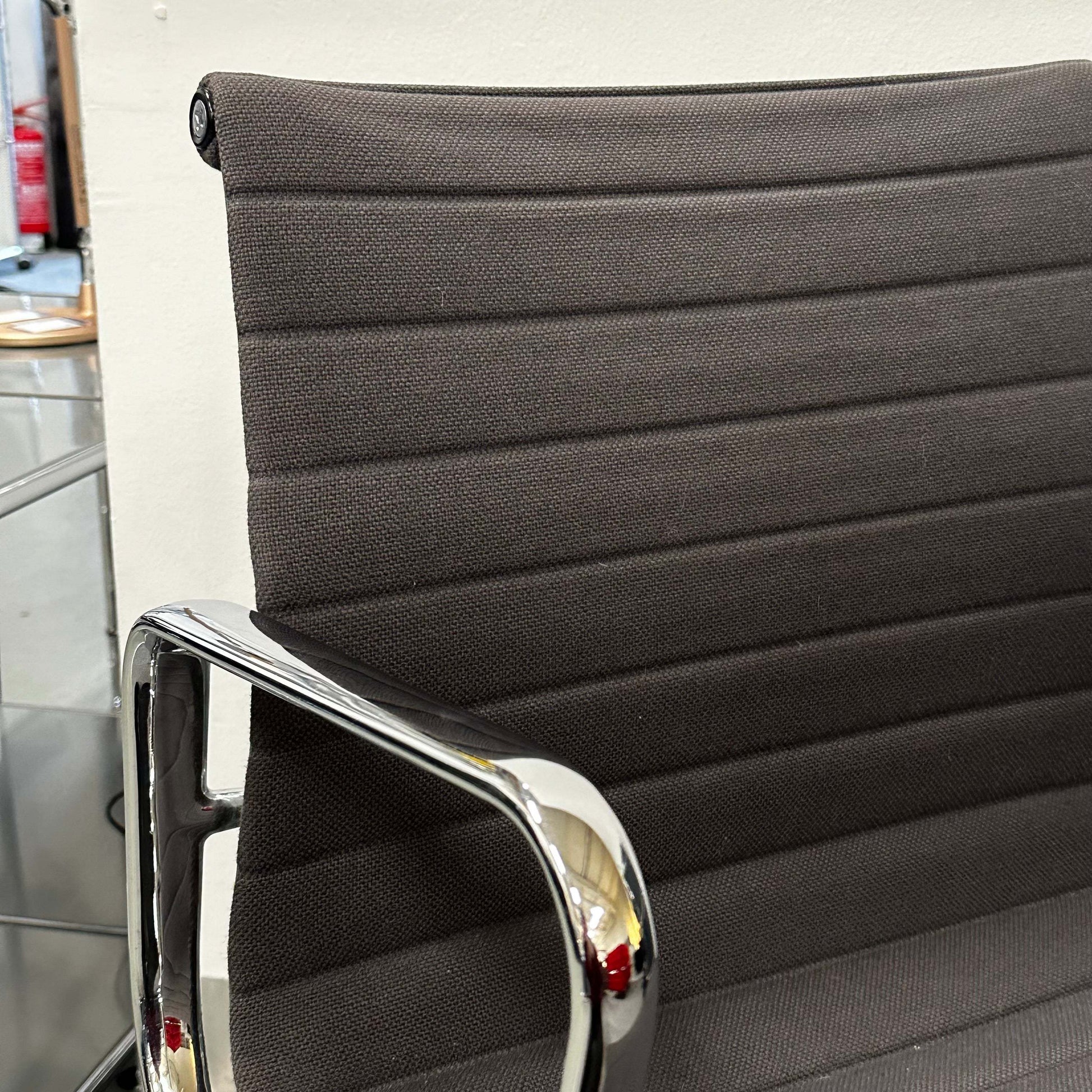 Close-up of Vitra EA 107 Hopsak anthracite non-rotating visitor chair with chrome armrest and textured fabric upholstery.