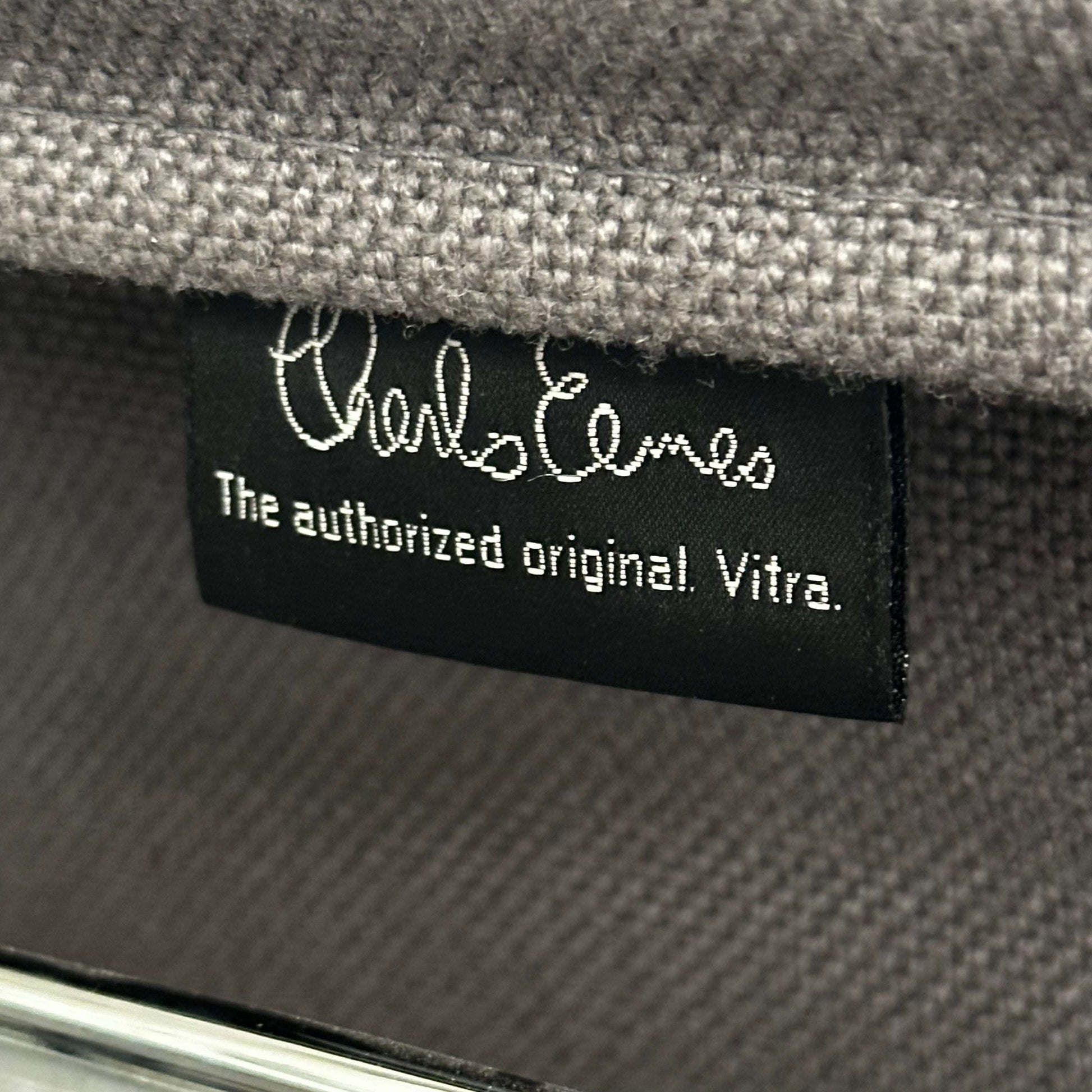 Close-up of a Vitra EA 107 chair label on medium grey hopsak fabric, non-swivel model