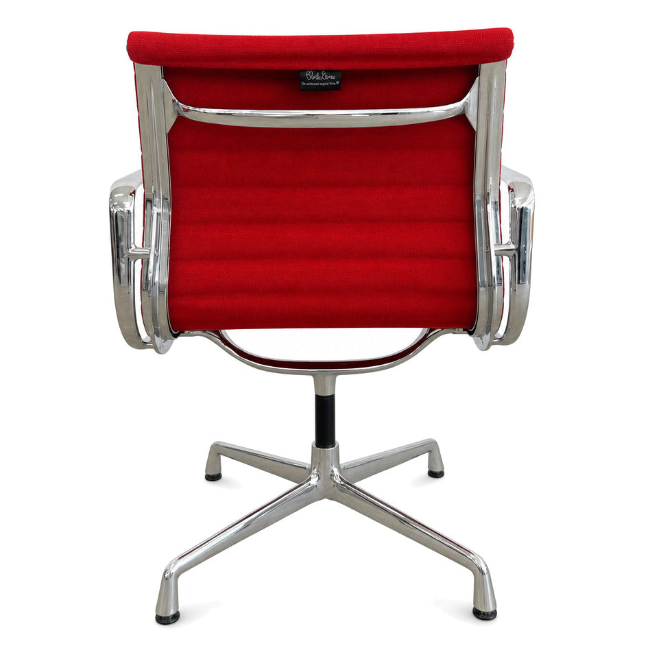 Vitra Eames Alu Chair EA 108 mit rotem Hopsak-Bezug und verchromtem Drehgestell in Rückansicht.