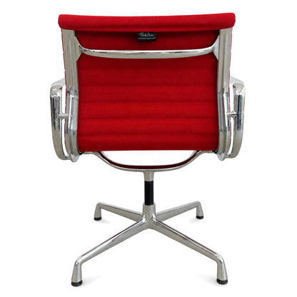 Vitra Eames Alu Chair EA 108 mit rotem Hopsak-Bezug und verchromtem Drehgestell in Rückansicht.