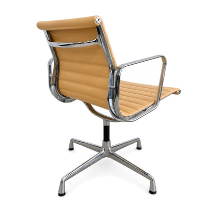 Vitra EA 108 Alu Chair in cashew-farbenem Leder mit verchromtem Gestell und Armlehnen auf weißem Hintergrund.