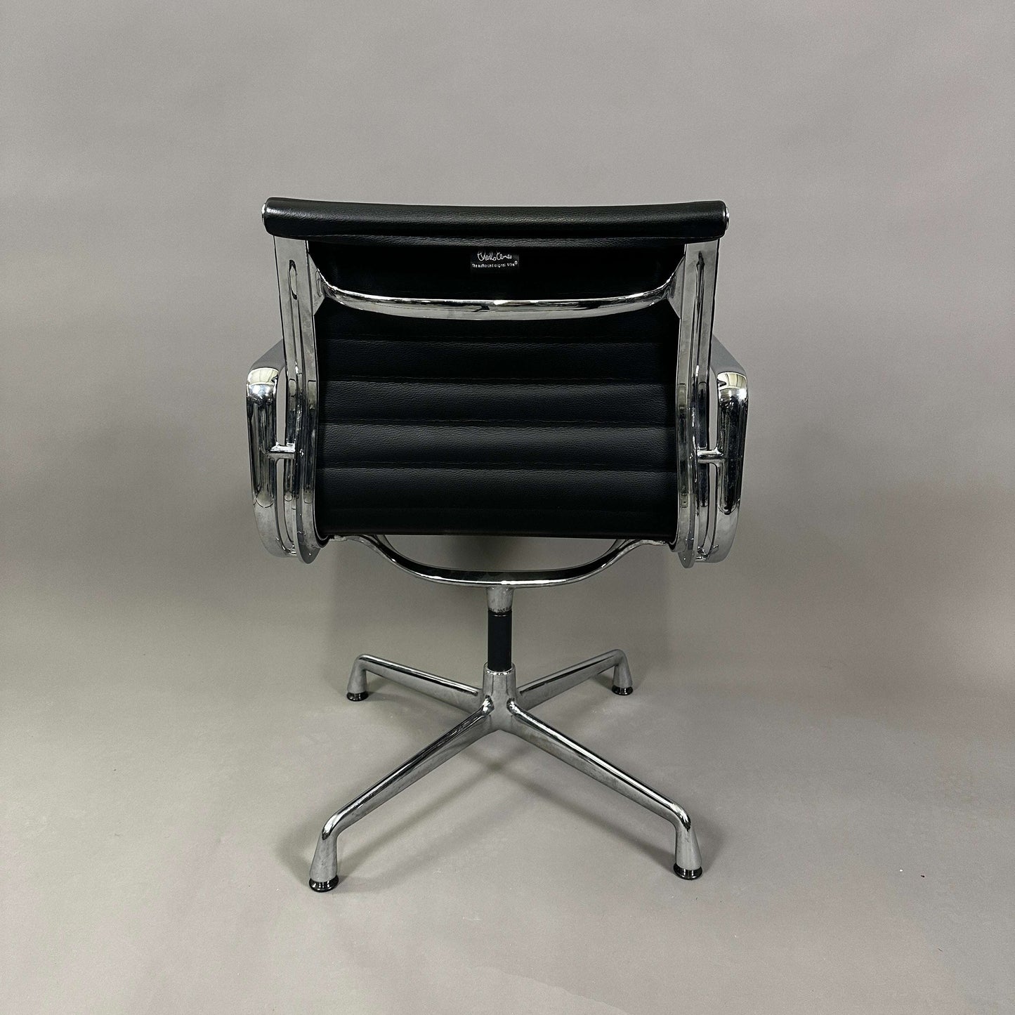 Vitra EA 108 black leather swivel office chair with chrome aluminum frame viewed from back