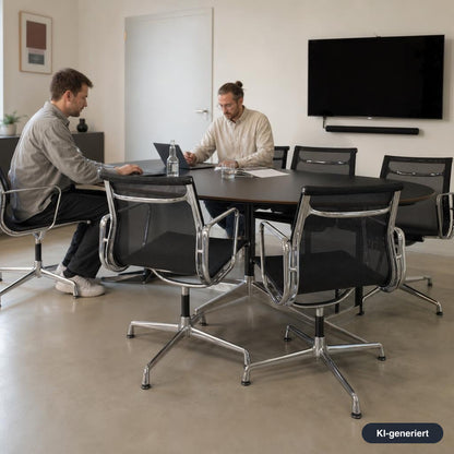 Vitra EA 108 Bürostuhl mit schwarzem Netzbezug und poliertem Aluminiumgestell an einem Konferenztisch.