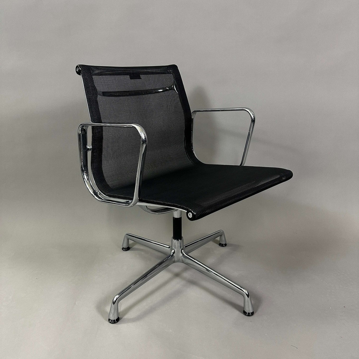 Vitra EA 108 black mesh swivel chair with chrome frame and armrests
