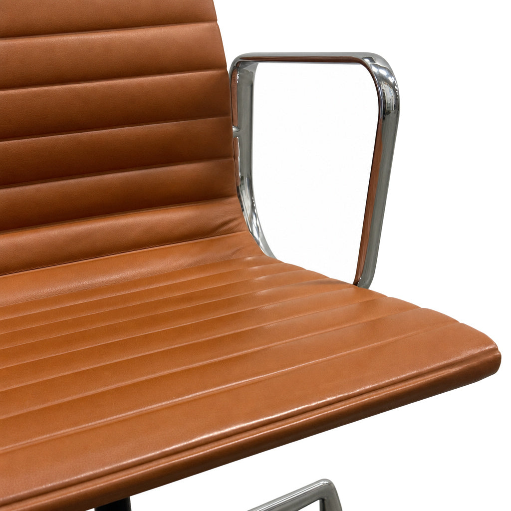 Vitra EA 108 Eames Alu Chair in cognac Premium Leder mit poliertem Aluminium-Gestell und markanter Quersteppung.