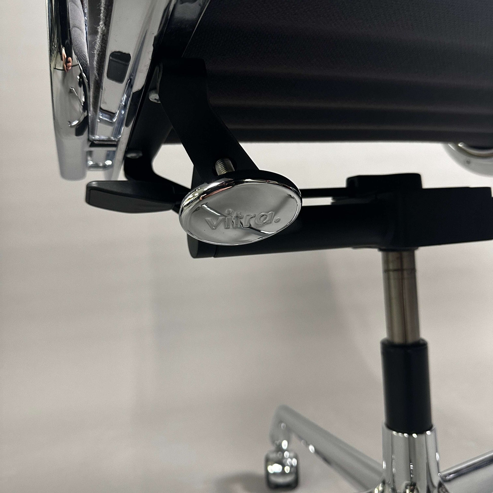 Nahaufnahme des verchromten Gestells und Verstellmechanismus des Vitra EA 117 Bürostuhls mit grauem Hopsak-Bezug