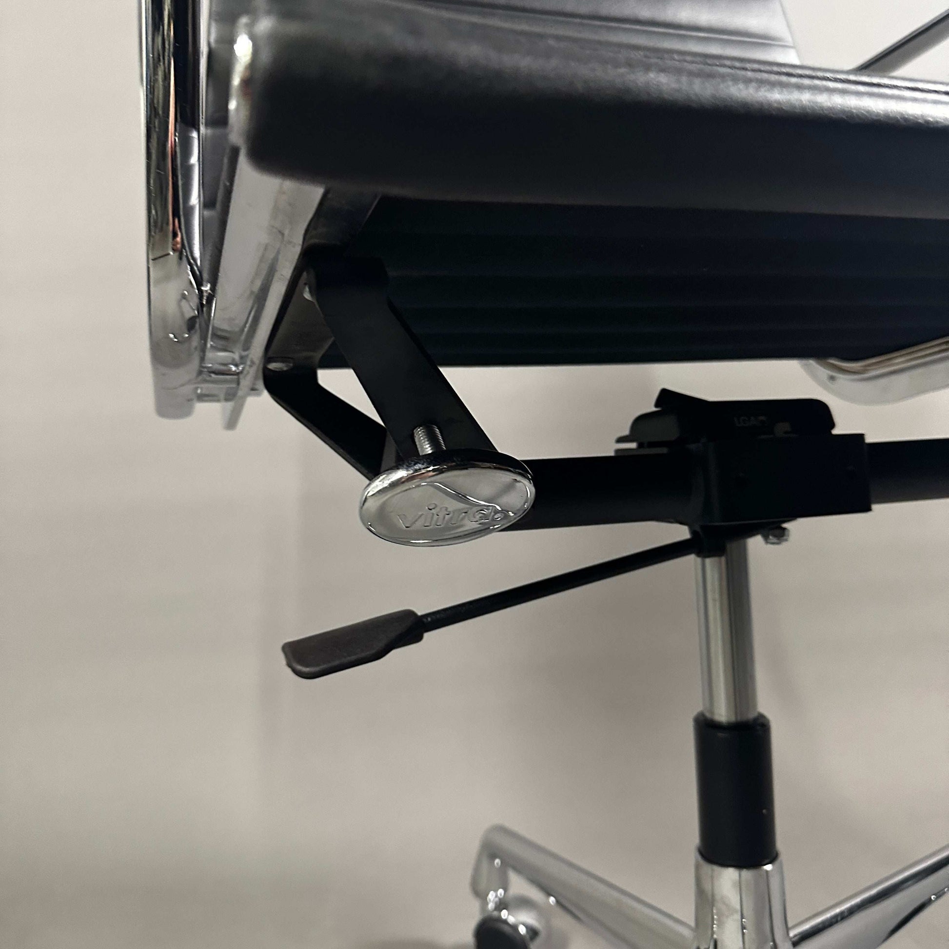 Detailaufnahme der verstellbaren Mechanik am Vitra EA 117 Bürostuhl aus schwarzem Leder mit Chromgestell