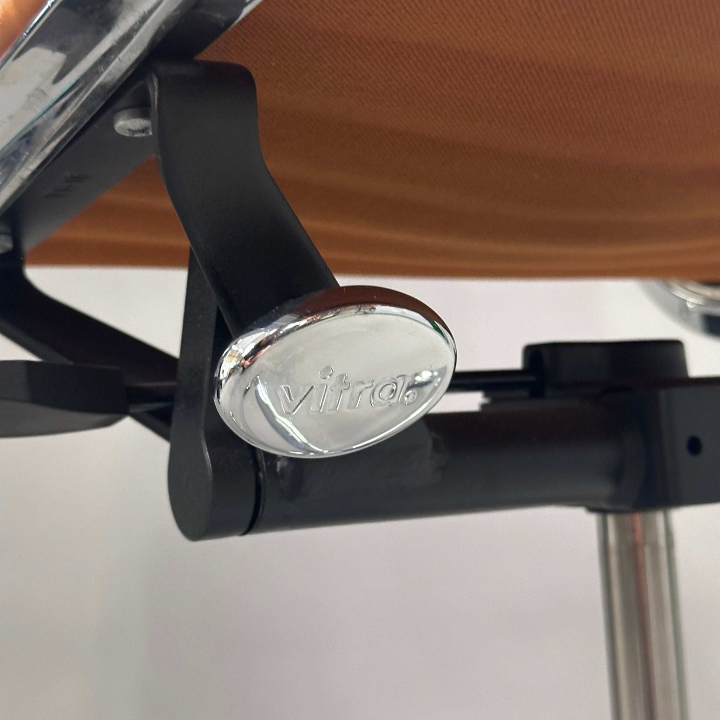 Vitra EA 117 Stuhl Hebel aus Chrom mit Vitra Logo am Premiumleder Stuhl in hellbraun