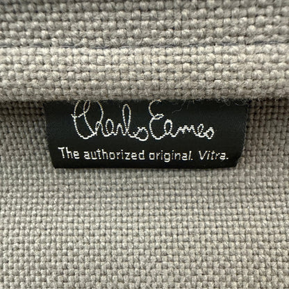 Schwarzes Charles Eames Label auf hellgrauem, strukturiertem Hopsak-Stoffbezug eines Vitra EA 119 Bürostuhls.