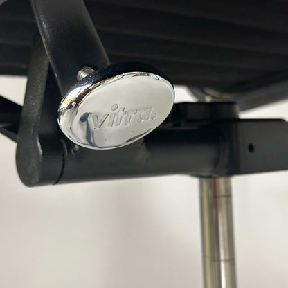 Close-up of Vitra EA 119 Hopsak black chair's adjustable mechanism with black frame and chrome detail