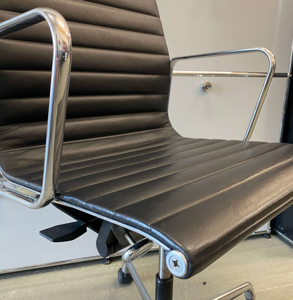 Close-up of Vitra EA 119 black leather office chair with high back and polished aluminum frame