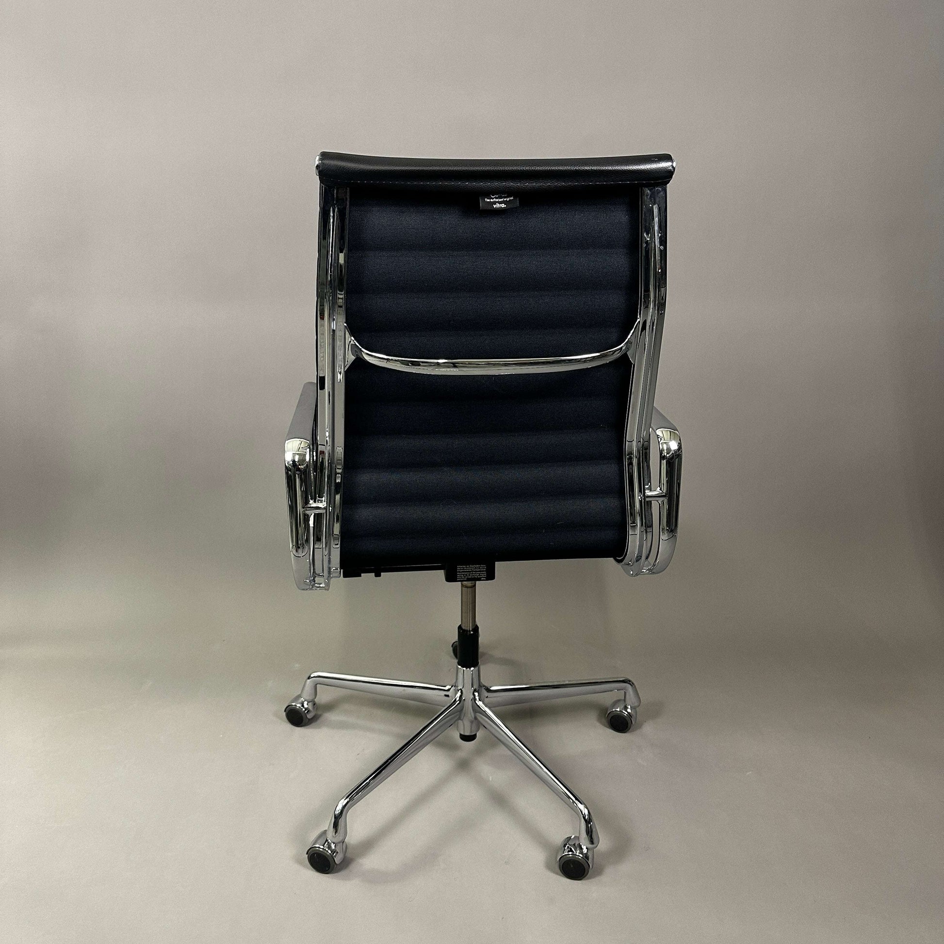 Vitra EA 119 office chair with black leather upholstery and chrome frame viewed from the back