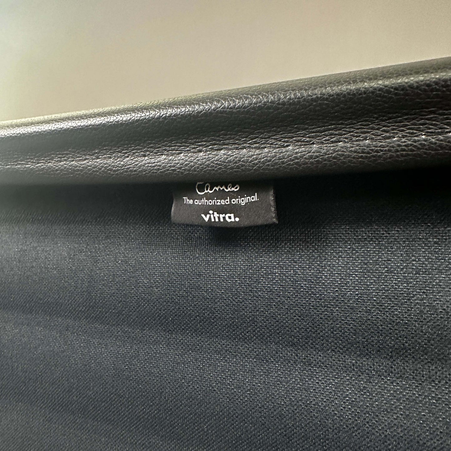Close-up of Vitra EA 119 black leather chair label showing authentic branding and high-quality material details