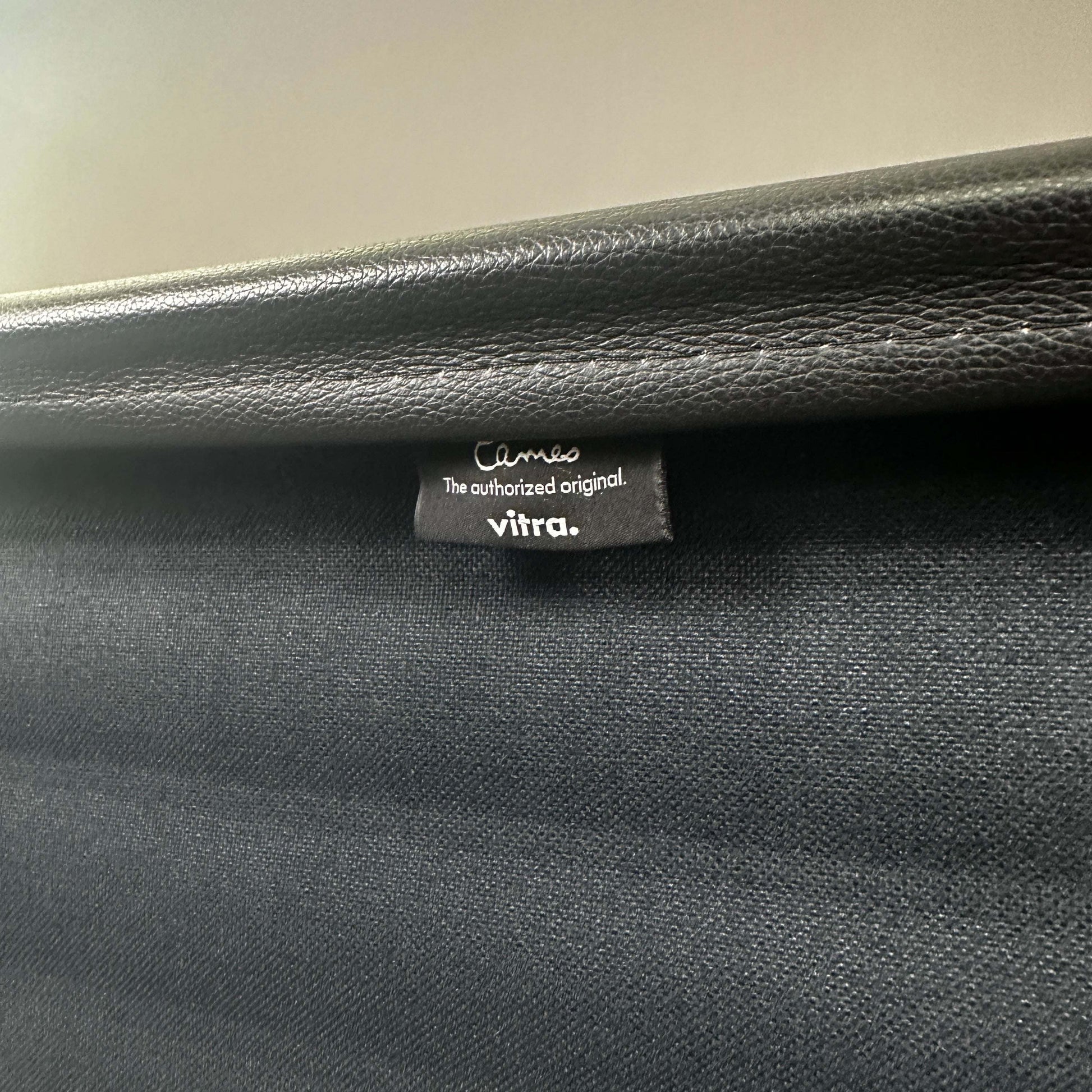 Close-up of Vitra EA 119 black leather chair label showing authentic branding and high-quality material details